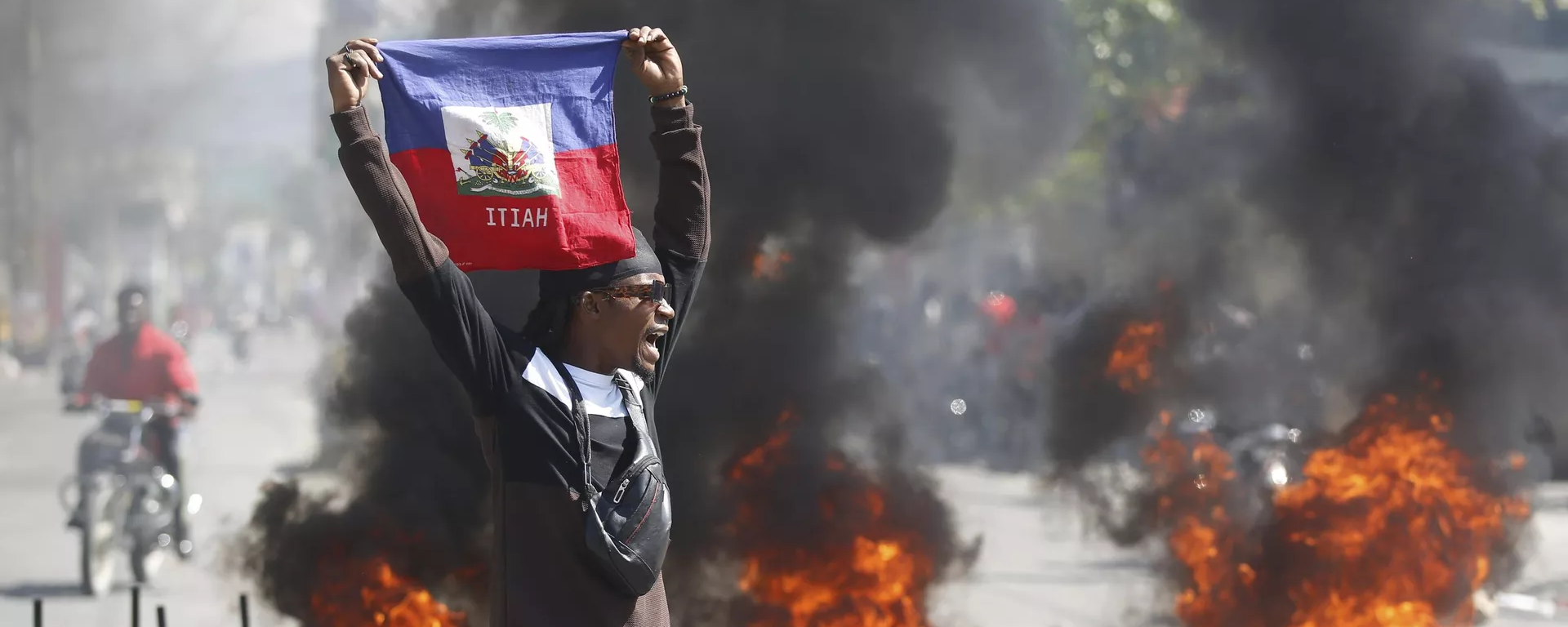 Manifestante segura bandeira do Haiti durante protesto que pede a saída do primeiro-ministro, Ariel Henry, em meio à escalada da violência no país. Porto Príncipe, 2 de março de 2024 - Sputnik Brasil, 1920, 09.03.2024