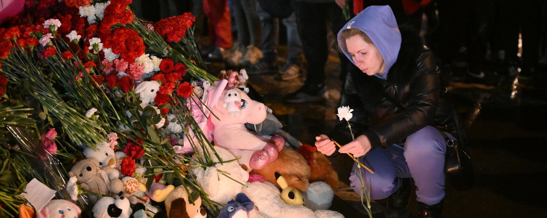 Mulher acende uma vela em um memorial feito por residentes locais, perto do teatro Crocus, em memória às vítimas do ataque terrorista. Rússia, 23 de março de 2024 - Sputnik Brasil, 1920, 23.03.2024