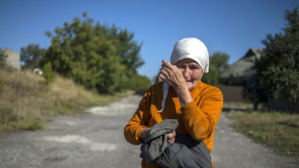 Uma mulher enxuga lágrimas perto de um comboio de veículos do 38º Comboio Humanitário russo para Donetsk, 17 de setembro de 2015 - Sputnik Brasil