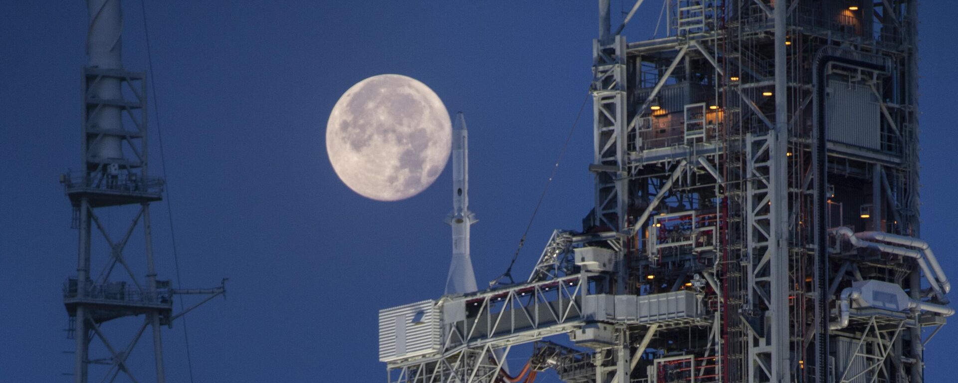 Lua cheia vista atrás do Sistema de Lançamento Espacial (SLS, na sigla em inglês) Artemis I e da espaçonave Orion, no Complexo de Lançamento 39B, no Centro Espacial Kennedy, da NASA. Flórida, 14 de junho de 2022 - Sputnik Brasil, 1920, 01.04.2024