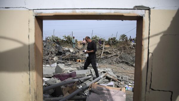 Palestinos inspecionam as ruínas de um prédio residencial após um ataque aéreo israelense em Rafah, Faixa de Gaza, 29 de março de 2024 - Sputnik Brasil