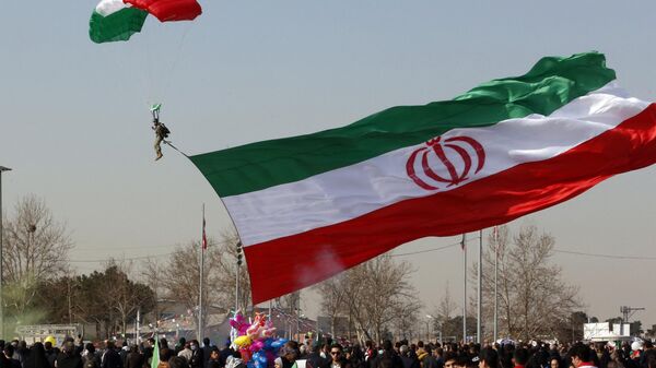 Um soldado pousando de paraquedas hasteia uma bandeira nacional iraniana enquanto as pessoas se reúnem para marcar o 45º aniversário da Revolução Islâmica em Teerã. Irã, 11 de fevereiro de 2024 - Sputnik Brasil