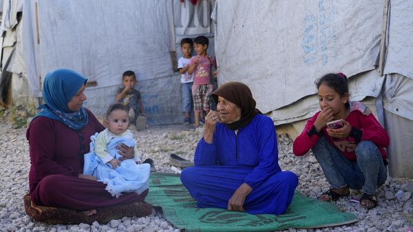 Família síria sentada em frente à sua tenda em um campo de refugiados na cidade de Bar Elias, no Vale do Bekaa, no Líbano, em 13 de junho de 2023 - Sputnik Brasil