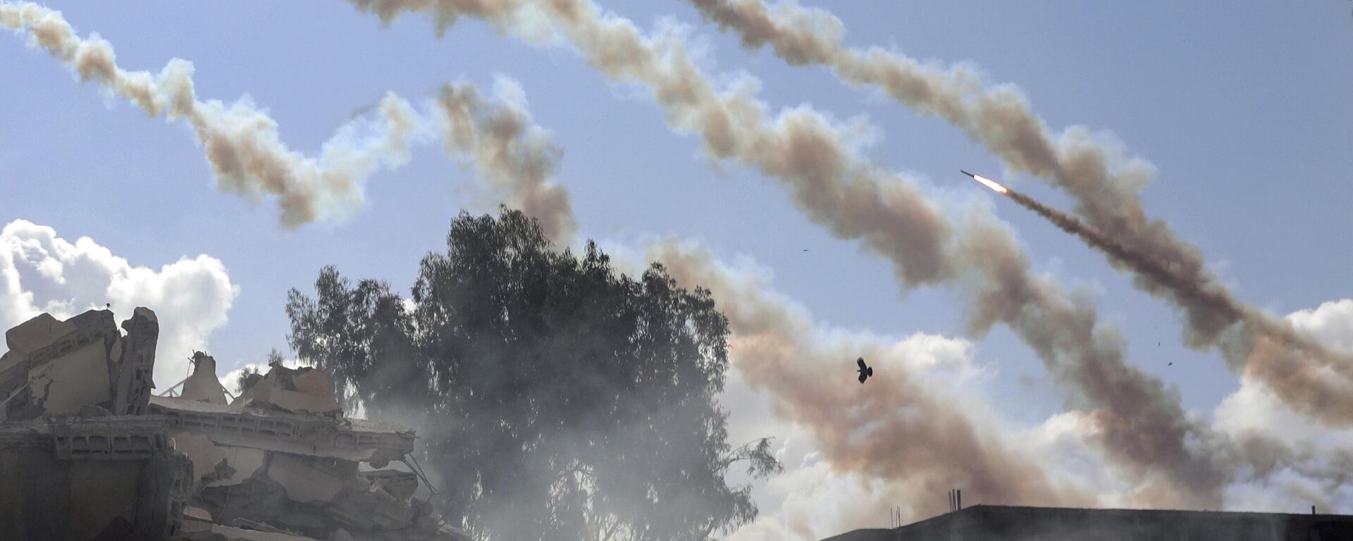 Foguetes são disparados da Faixa de Gaza em direção a Israel em meio a edifícios destruídos, após ataques aéreos israelenses na Cidade de Gaza. Faixa de Gaza, 19 de outubro de 2023 - Sputnik Brasil, 1920, 24.04.2024