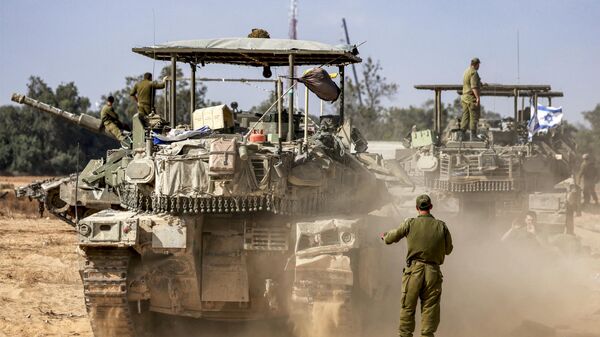 Um soldado do Exército israelense gesticula atrás de um tanque de batalha principal em movimento enquanto as forças se reúnem em uma posição perto da fronteira com a Faixa de Gaza, no sul de Israel, em 30 de abril de 2024 - Sputnik Brasil