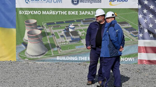 Funcionários ao lado de um cartaz durante a cerimônia de lançamento da implementação das atividades preparatórias antes da construção das unidades de energia 5 e 6 da usina nuclear de Khmelnitsky (KhNPP, na sigla em inglês) usando a tecnologia norte-americana Westinghouse, perto da cidade ucraniana de Khmelnitsky, 11 de abril de 2024 - Sputnik Brasil