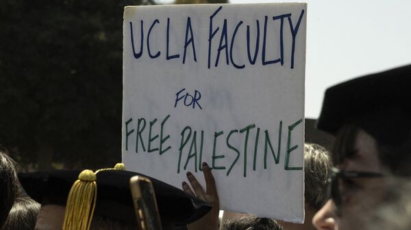 Manifestante segura cartaz dizendo Faculdade UCLA pela Palestina Livre enquanto membros da faculdade e da equipe da Universidade de Califórnia de Los Angeles (UCLA, na sigla em inglês) se manifestam ao lado de acampamento pró-palestino no campus da universidade em Los Angeles, Califórnia, EUA, 1º de maio de 2024 - Sputnik Brasil