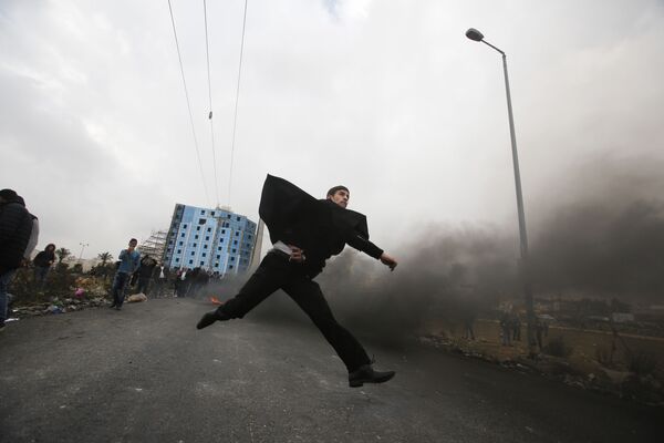 Um advogado palestino atira pedras em direção às tropas israelenses durante os confrontos com as tropas israelenses perto do povoado de Beit El, a pouca distância da cidade de Ramallah, na Cisjordânia, em 13 de dezembro de 2017 - Sputnik Brasil