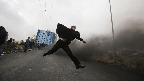 Um advogado palestino atira pedras em direção às tropas israelenses durante os confrontos com as tropas israelenses perto do povoado de Beit El, a pouca distância da cidade de Ramallah, na Cisjordânia, em 13 de dezembro de 2017 - Sputnik Brasil