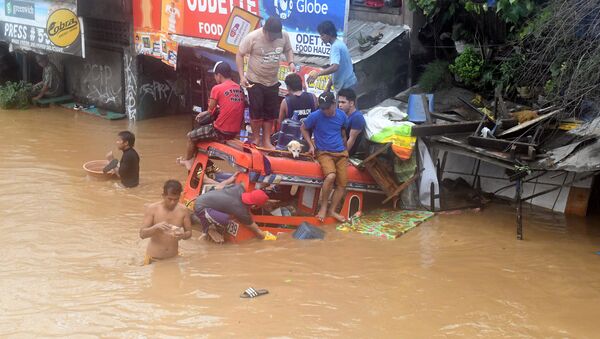 Filipinos estão sentados em um veículo parcialmente afundado em uma das ruas inundadas na sequência da tormenta, em 22 de dezembro de 2017 - Sputnik Brasil