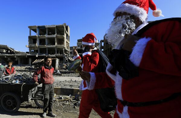 Menino sírio sorri ao ver homens vestidos de Papai Noel em Raqqa, Síria - Sputnik Brasil