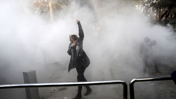 طالبة جامعية في مظاهرة داخل جامعة طهران وقت إلقاء قنبلة دخان من قبل الشرطة الإيرانية لمكافحة الشغب - Sputnik Brasil