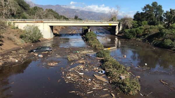 An abandoned car is seen stuck in flooded water on the 101 freeway after a mudslide in Montecito, California, U.S. January 10, 2018 - Sputnik Brasil