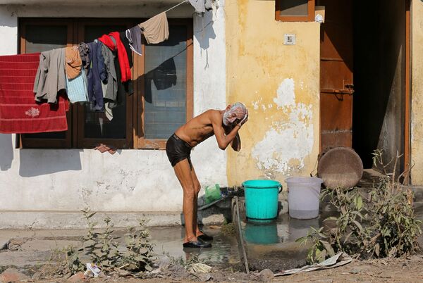 Homem toma banho no mercado na cidade indiana de Jammu - Sputnik Brasil