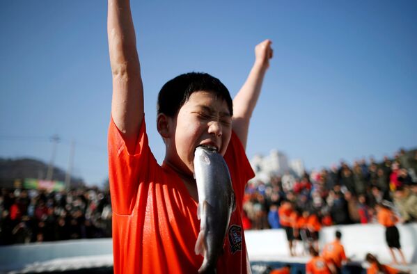 Menino contente por ter apanhado um peixe com as mãos na cidade sul-coreana de Hwacheon - Sputnik Brasil
