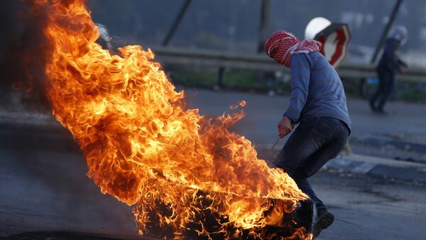 Manifestante palestino com um pneu em chamas durante confrontos com as forças de segurança israelenses na cidade de Nablus, na Cisjordânia - Sputnik Brasil