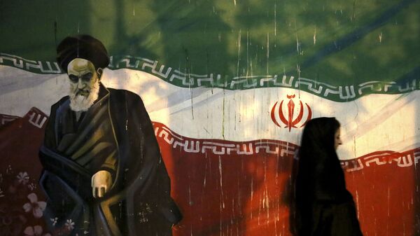 Iraniana coberta passa por muro que retrata o revolucionário aiatolá Ruhollah Khomeini e a bandeira iraniana nacional, pintada na parede da antiga Embaixada dos EUA, em Teerã, no Irã - Sputnik Brasil