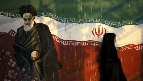 Iraniana coberta passa por muro que retrata o revolucionário aiatolá Khomeini e a bandeira iraniana nacional, pintada na parede da antiga embaixada dos EUA, em Teerã, Irã - Sputnik Brasil