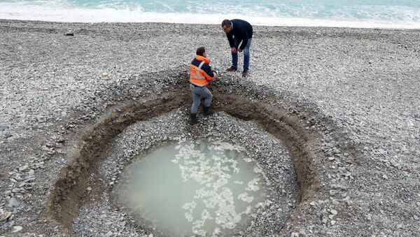 Um agente de obras municipais examina uma cratera de 2 metros de profundidade e 5 metros de largo  que se formou na cidade francesa de Nice em 1 de fevereiro de 2018 - Sputnik Brasil