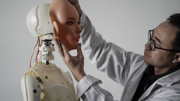 Engenheiro segurando um rosto de silicone diante de um robô na fábrica da EXDOLL - Sputnik Brasil