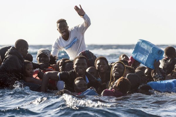 Migrantes em um barco semiafundado pedem socorro no mar Mediterrâneo - Sputnik Brasil