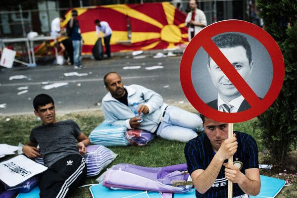 Protestos na Macedônia. Um manifestante empunha o pequeno cartaz com uma foto de premeiro-ministro macedônio Nikola Gruevski durante o protesto antigovernamental no centro de Skopje no 17 de maio de 2015. Mais de 20.000 pessoas se reuniram na capital da Macedónia para exigir a renúncia do governo do primeiro-ministro Nikola Gruevski, que é responsavel pela crise política profunda e um surto de violência no país. - Sputnik Brasil