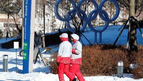 Voluntários caminham ao lado dos anéis olímpicos no resort Alpensia em Pyeongchang, Coreia do Sul - Sputnik Brasil