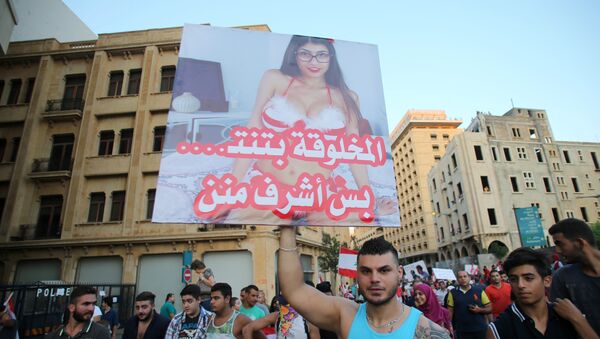 A Lebanese protester raises a poster bearing an image of Lebanese origin Porn Star Mia Khalifa and reading It is true that this woman does sex but she is more decent then them during a mass rally against a political class seen as corrupt and incapable of providing basic services on August 29, 2015 at the iconic Martyrs Square in Beirut - Sputnik Brasil
