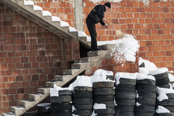 Um homem limpa a escada da neve na aldeia Mramor, perto de Pristina - Sputnik Brasil