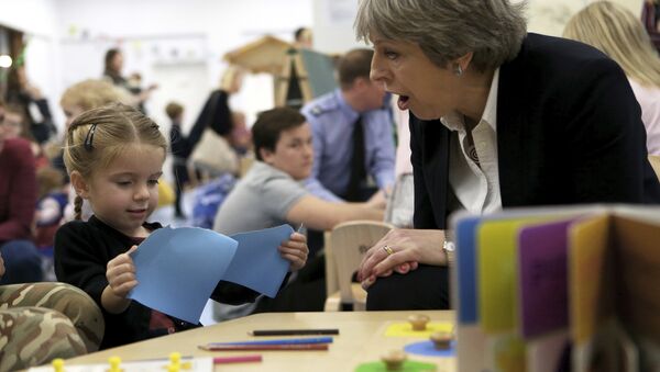Theresa May, primeira-ministra do Reino Unido, fala com uma criança no jardim de infância durante uma visita a uma das duas bases militares britânicas no mediterrâneo do leste, na ilha de Chipre. - Sputnik Brasil