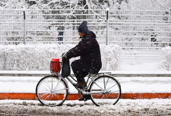 Homem andando de bicicleta durante nevasca na cidade chinesa de Shenyang - Sputnik Brasil