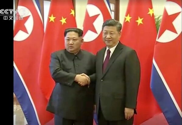 Líder norte-coreano, Kim Jong-un, aperta a mão do seu homólogo chinês, Xi Jinping, durante seu histórico encontro bilateral celebrado entre 25 e 28 de março de 2018, em Pequim - Sputnik Brasil
