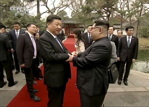 Os líderes norte-coreano, Kim Jong-un, e chinês, Xi Jinping, saúdam um ao outro durante encontro não oficial em Pequim em 25 de março de 2018 - Sputnik Brasil