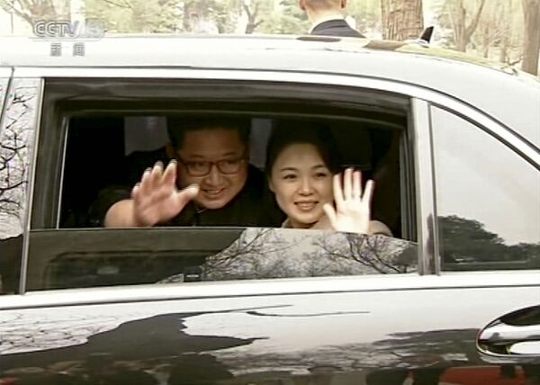 Líder da Coreia do Norte, Kim Jong-un, junto com sua esposa, Ri Sol Ju, acenam as mãos de um carro ao se despedirem do presidente chinês, Xi Jiping, e de sua esposa Peng Liyuan, em Pequim, em 28 de março de 2018 - Sputnik Brasil