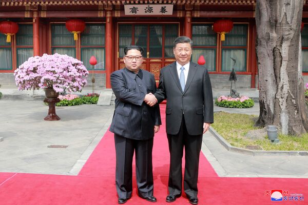 Líder norte-coreano, Kim Jong-un, aperta a mão do seu homólogo chinês, Xi Jinping - Sputnik Brasil