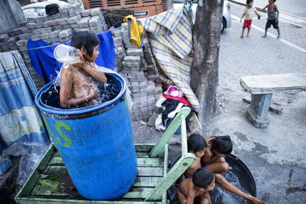 Crianças tomam banho em uma das ruas de Manila, capital filipina - Sputnik Brasil