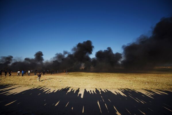 Manifestantes palestinos durante os confrontos com soldados israelenses na fronteira entre a Faixa de Gaza e Israel - Sputnik Brasil