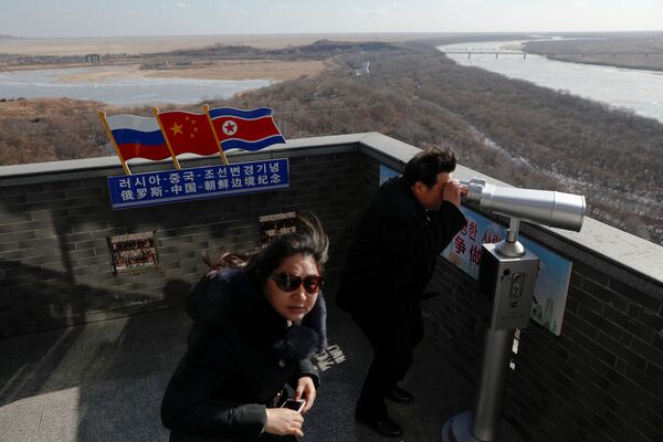 Turista usa binóculo para olhar à Coreia do Norte de uma torre construída na parte chinesa da tripla fronteira entre a Rússia, a China e a Coreia do Norte - Sputnik Brasil