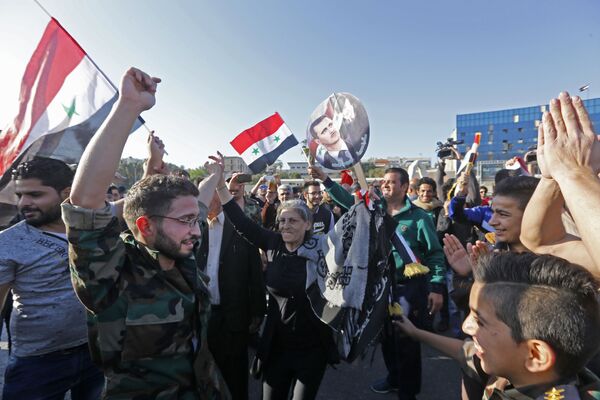 Cidadãos sírios com retratos do presidente Bashar Assad e com bandeiras da Síria durante uma manifestação contra os ataques aéreos da coalizão liderada pelos EUA - Sputnik Brasil