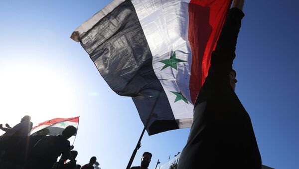 Participantes de uma manifestação contra os ataques aéreos da coalizão internacional na Síria agitam bandeiras da República Árabe da Síria - Sputnik Brasil