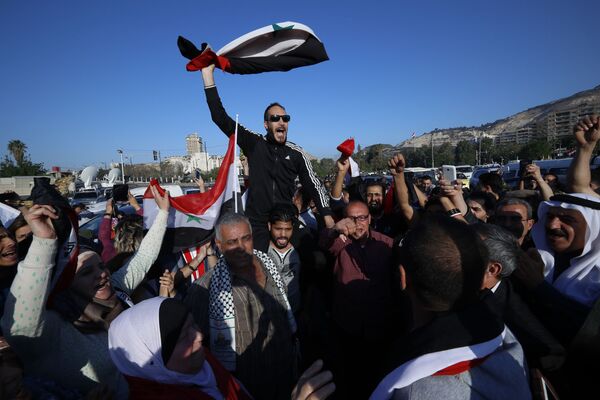 Cidadãos sírios agitam bandeiras da Síria durante uma manifestação contra os ataques aéreos da coalizão liderada pelos EUA - Sputnik Brasil