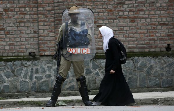 Estudante muçulmana passa perto de um policial indiano durante protesto contra estupros na cidade de Srinagar, Caxemira, Índia. - Sputnik Brasil