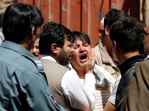 Um homem choram enquanto outros tentam confortá-lo no local de um ataque suicida em Cabul. - Sputnik Brasil