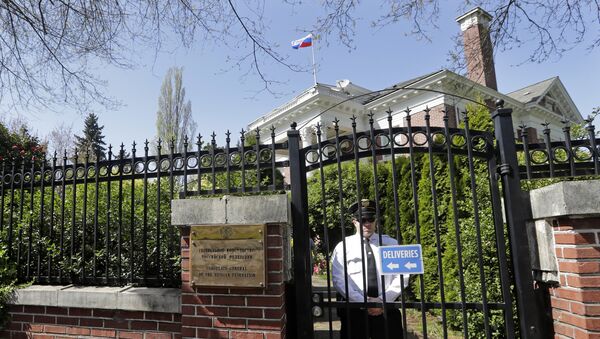 Enquanto a bandeira russa permanece hasteada, um oficial de segurança está atrás dos portões da residência antiga do cônsul russo, 25 de abril de 2018, Seattle, EUA - Sputnik Brasil