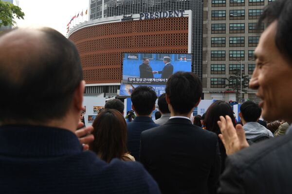 Pessoas em Seul aplaudem observando a transmissão do encontro histórico entre seus líderes ao apertarem as mãos na zona desmilitarizada que separa as duas Coreias - Sputnik Brasil