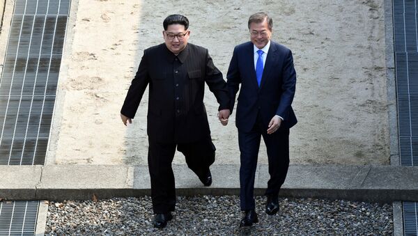 Líder norte-coreano Kim Jong-un e seu homólogo sul-coreano Moon Jae-in atravessam a linha que demarca a zona desmilitarizada na aldeia fronteiriça de Panmunjom, 27 de abril de 2018 - Sputnik Brasil