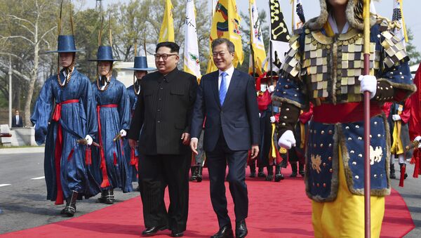 O líder norte-coreano, Kim Jong-un, à esquerda, e  o líder sul-coreano, Moon Jae-in, à direita, caminham juntos na fronteira do vilarejo de Panmunjom, zona desmilitarizada, 27 de abril de 2018 - Sputnik Brasil