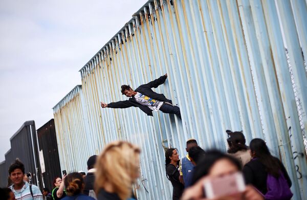 Participante de uma manifestação de imigrantes da América Central sobe ao muro que divide o México e os EUA - Sputnik Brasil