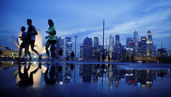 Joggers run past as the skyline of Singapore's financial district is seen in the background - Sputnik Brasil
