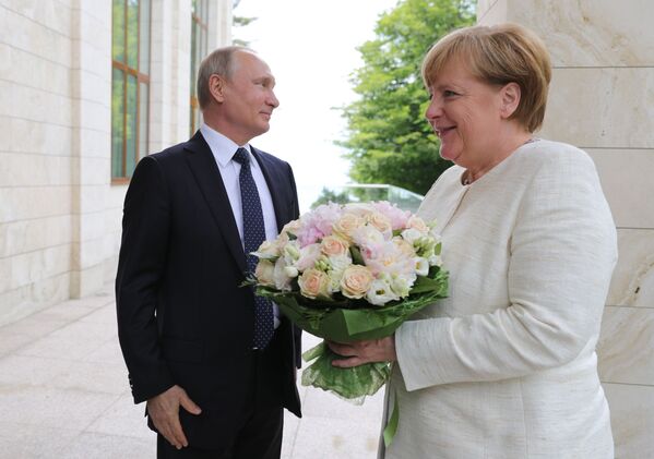 O presidente da Rússia, Vladimir Putin, oferece um buquê de flores à chanceler da Alemanha, Angela Merkel, antes da reunião dos dois líderes em Sochi, na Rússia - Sputnik Brasil